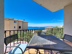 Ein Balkon mit Tisch und Stühlen und Blick auf die Küste.