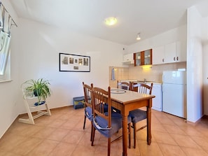 Un coin repas avec une table et des chaises en bois, une plante en pot et une photo encadrée accrochée au mur.