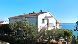 A coastal building with a tiled roof, a staircase, and a view of the sea. - Apartment Culić by Interhome (Trogir)