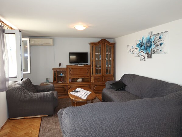 A living room with two grey sofas, a wooden cabinet, a TV, and a window with curtains. - Filip Jakov by Interhome (Trogir)