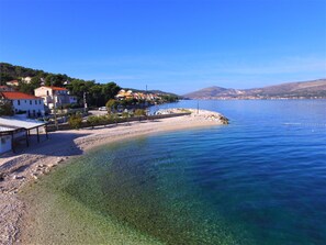 A coastal town with clear waters, a sandy beach, and buildings along the shore.