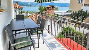 Ein Balkon mit Tisch und Stühlen und Blick auf das Meer, mit rotem Teppich.