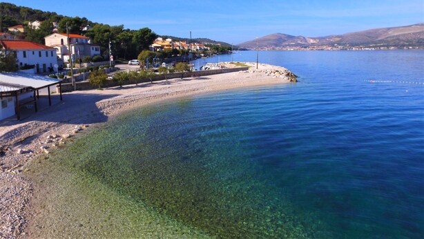 Eine Küstenstadt mit klarem Wasser, einem Sandstrand und Gebäuden entlang der Uferlinie.