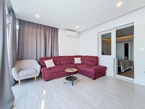 A modern living room with a red sofa, a small round table, and a light-colored armchair.