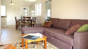 A living room with a sofa, a coffee table, and two wooden stools. There is a dining area with a table and chairs in the background. - Apartment Perisa by Interhome (Šibenik)