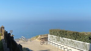 A coastal walkway with a wooden fence, a bicycle, and a clear view of the sea. - Les Pieds Dans L'eau ! Accès Direct sur la Plage de Bonne Source (Pornichet)