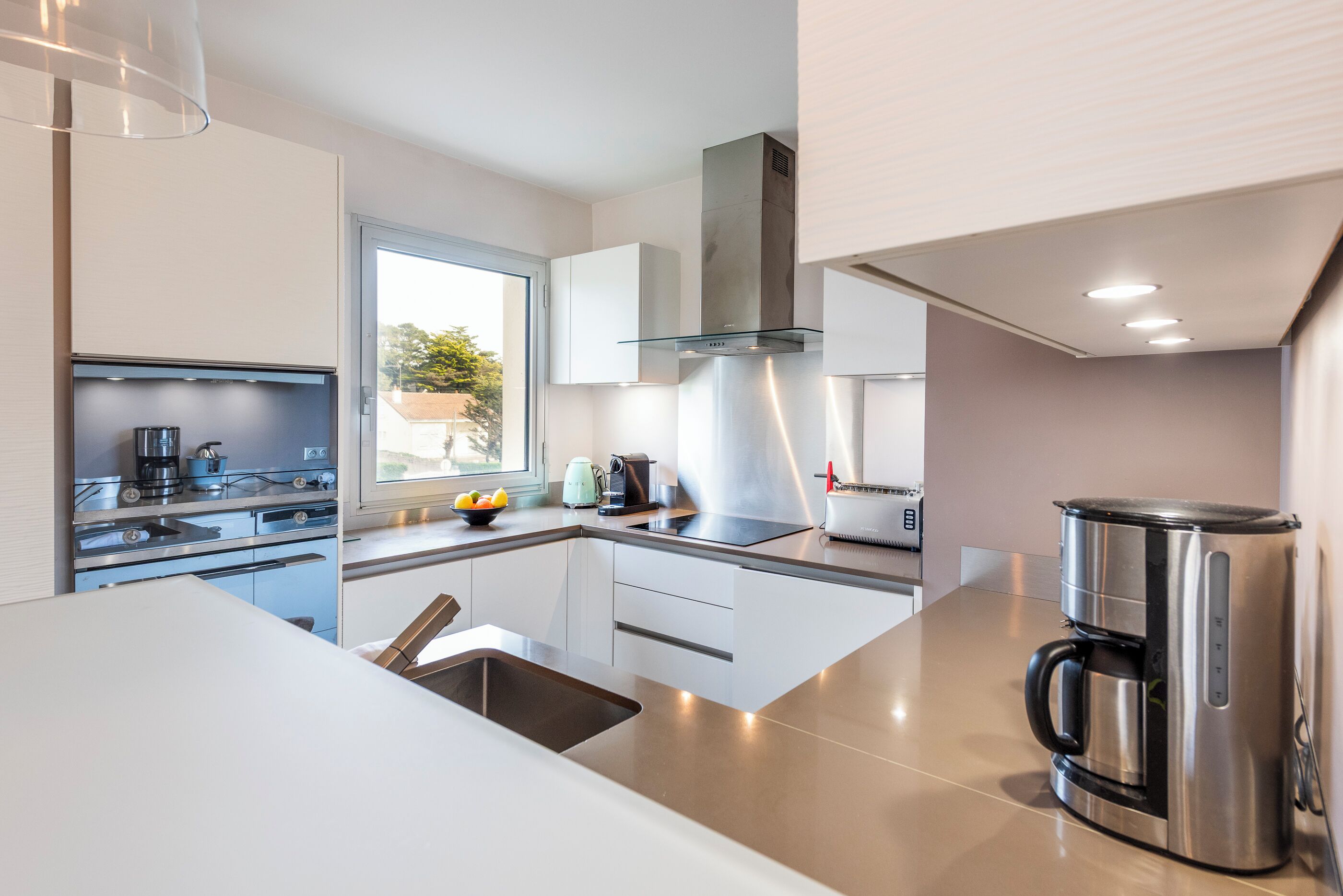 A modern kitchen with stainless steel appliances, a window, and a view of the outdoors.