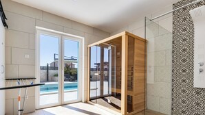 A modern bathroom with a glass shower enclosure, a wooden vanity, and a view of a swimming pool outside. - Vacation home Carmen by Interhome (Zaton (Šibenik))