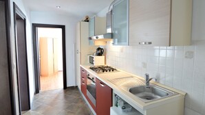 A modern kitchen with a gas stove, microwave, and stainless steel sink. - Apartment Josip by Interhome (Vodice)