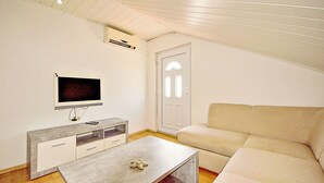 A modern, minimalistic living room with a flat-screen TV, a grey console table, and a beige sofa. - Apartment Josip by Interhome (Vodice)