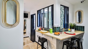 Une cuisine moderne avec un îlot central, des tabourets de bar noirs et un grand miroir.