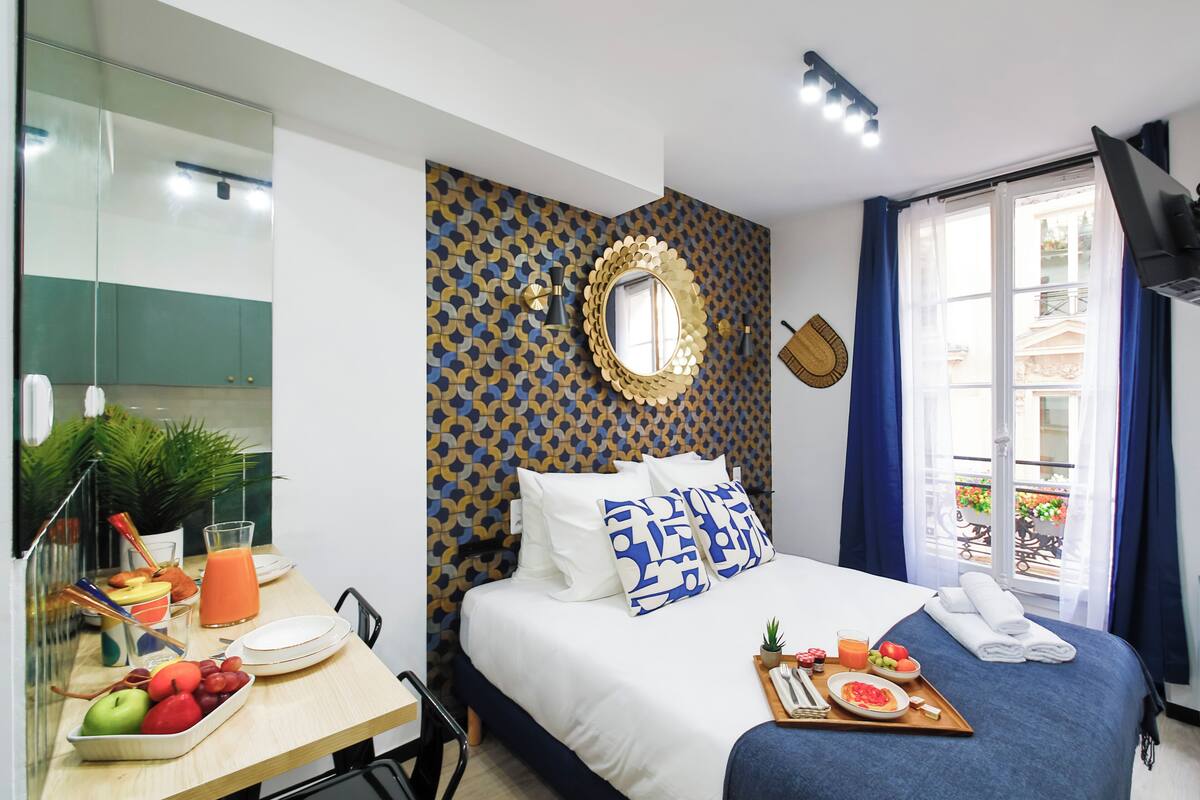 A hotel room with a bed, breakfast tray, and a window with curtains.