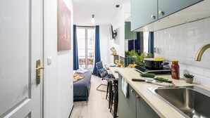 Une cuisine compacte comprenant un évier, un plan de travail et des placards. Il y a également un coin repas avec une table et des chaises.