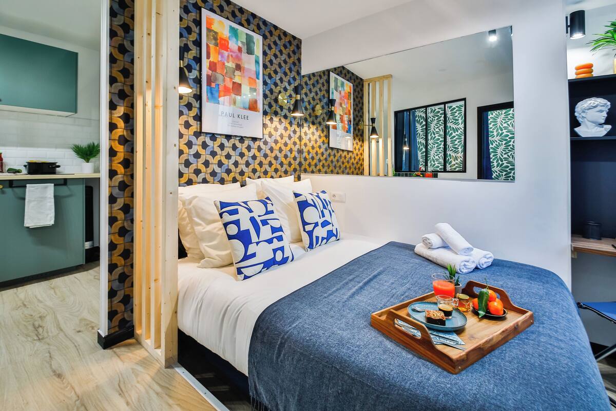 A modern hotel room with a bed, a breakfast tray, and artwork on the walls.