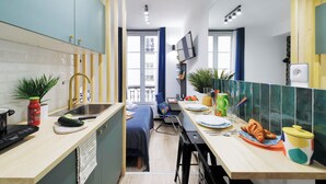 Une cuisine de taille réduite comprenant un évier, une cuisinière et un coin repas avec des chaises et une table.