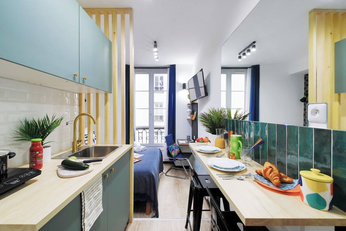 A compact kitchen with a sink, a stove, and a dining area with chairs and a table.