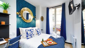 Une chambre d’hôtel comprenant un lit, un bureau, une télévision, une fenêtre avec des rideaux et une salle de bain.