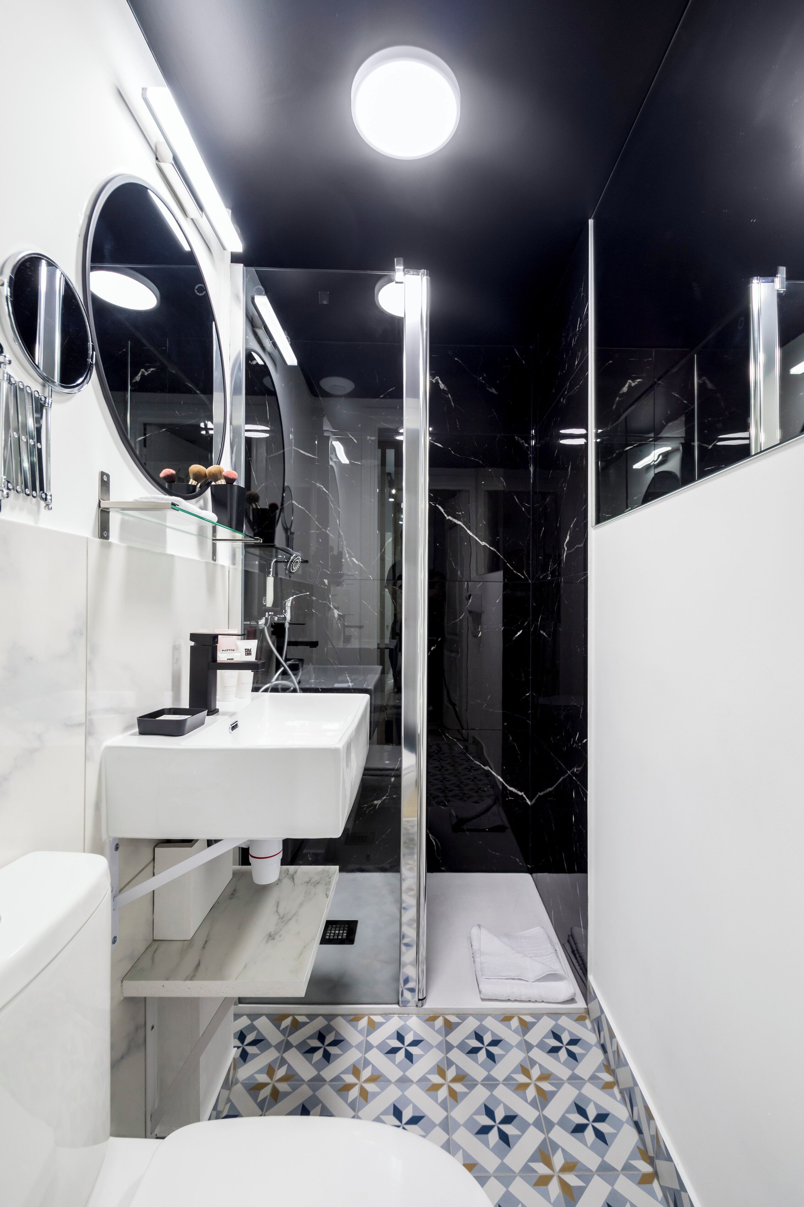 A modern bathroom with a white sink, a mirror, and a shower area.