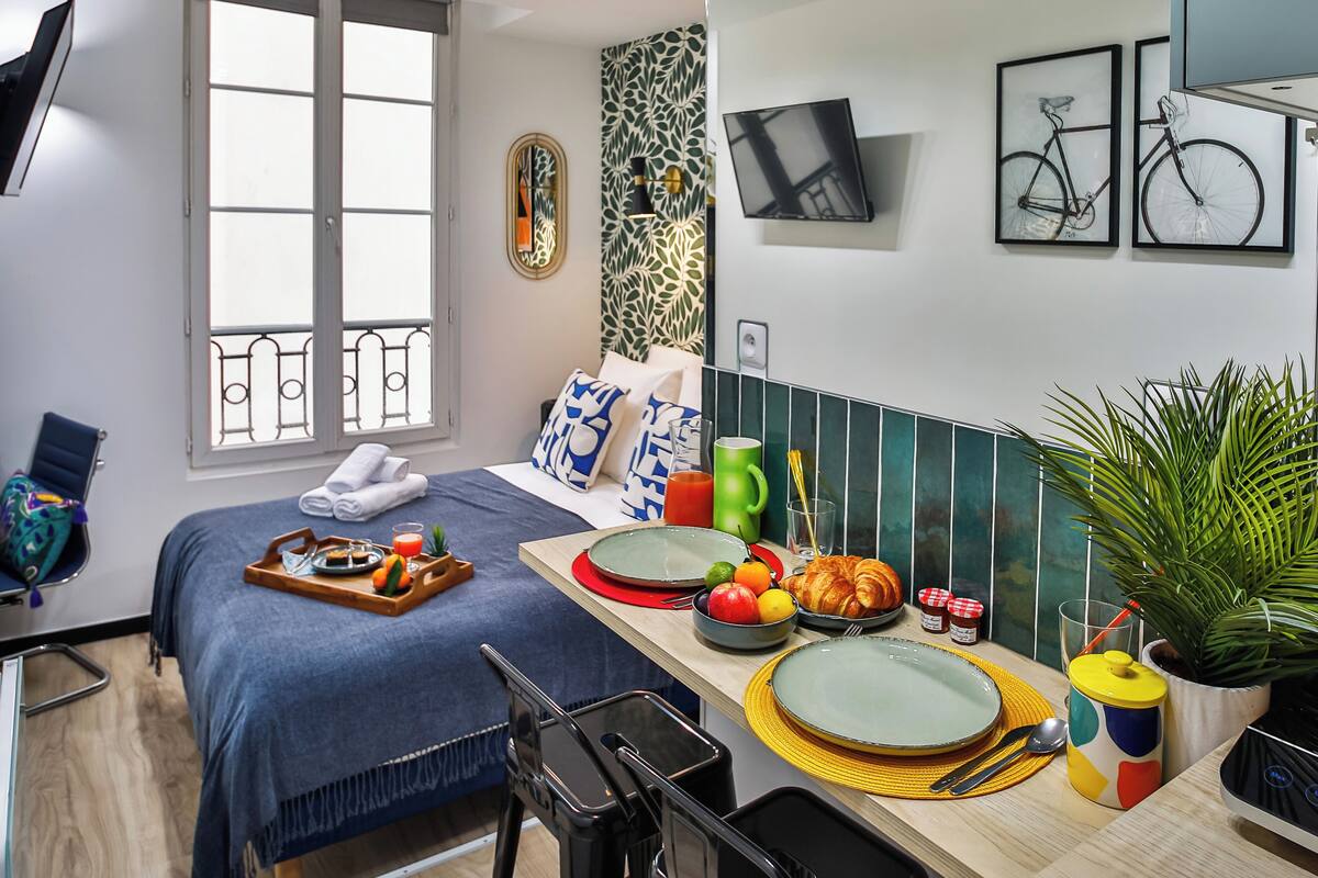A compact living space with a bed, dining area, and a small kitchenette.