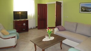 Ein Wohnzimmer mit einer Couch, einem Sessel, einem Holztisch und einem Fernseher.