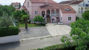 Eine rosa Villa mit Ziegeldach, einer zentralen Treppe und einem kleinen Balkon.