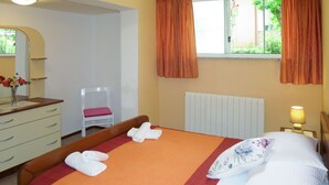 Ein Hotelzimmer mit einem Bett, einem Schminktisch, einem Sessel, einem Fenster mit Vorhängen und einer Lampe.