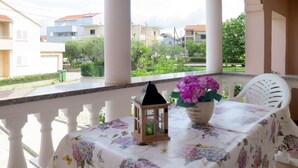 A balcony with a table covered in a floral tablecloth, a potted plant, and a lantern.