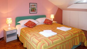 A bedroom with a bed, pillows, a nightstand, a lamp, and a wardrobe.