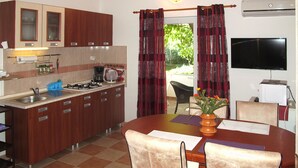 A compact kitchen with wooden cabinets, a gas stove, and a dining area with a table and chairs.