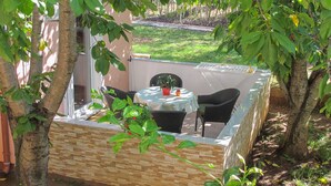 An outdoor patio area with a table and chairs, surrounded by trees and a stone wall.