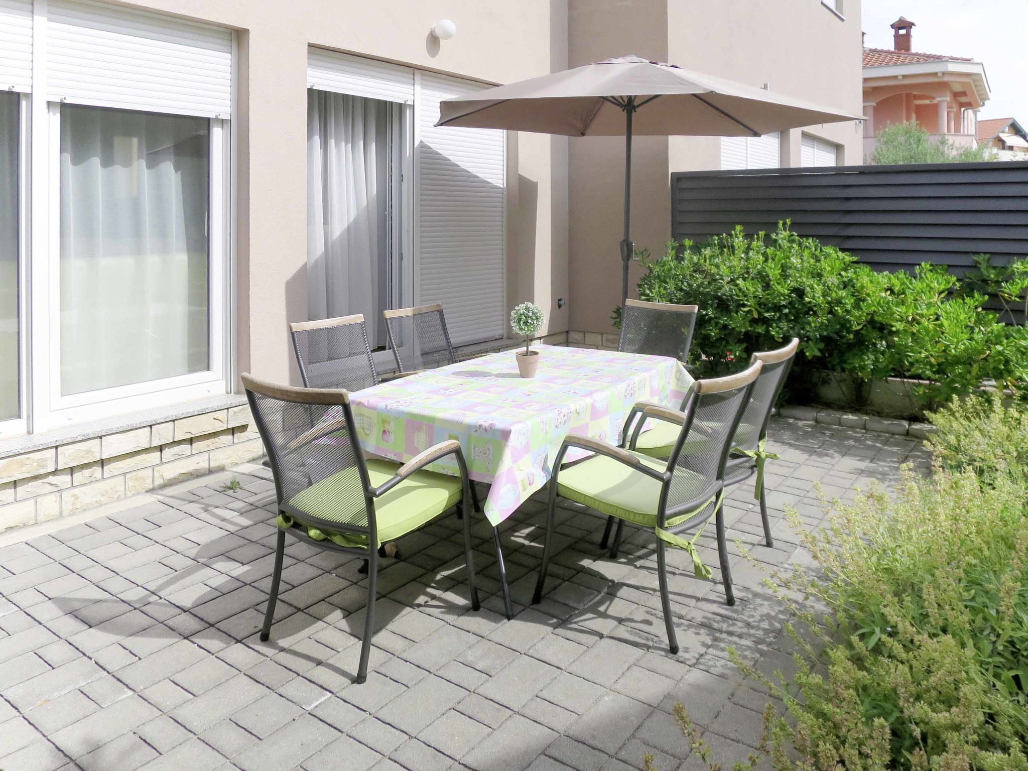 A patio with a table and chairs, a potted plant, and a large umbrella.