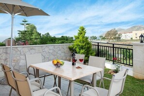 Eine Terrasse im Freien mit einem Tisch für zwei Personen, einer Weinflasche und einer Obstschale.