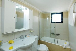 Ein modernes Badezimmer mit großem Spiegel, zwei Waschbecken, einer Duschkabine und einem Fenster.