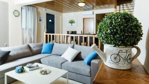 A modern living room with a grey sofa, a white coffee table, and a decorative plant in a bicycle-themed pot.