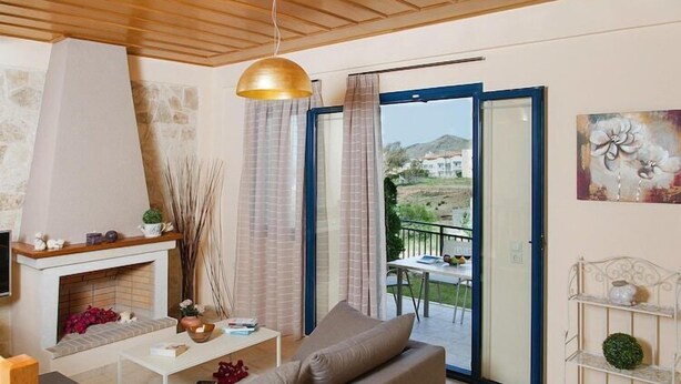 A living room with a fireplace, sofa, coffee table, and a view of the outdoors through a glass door.