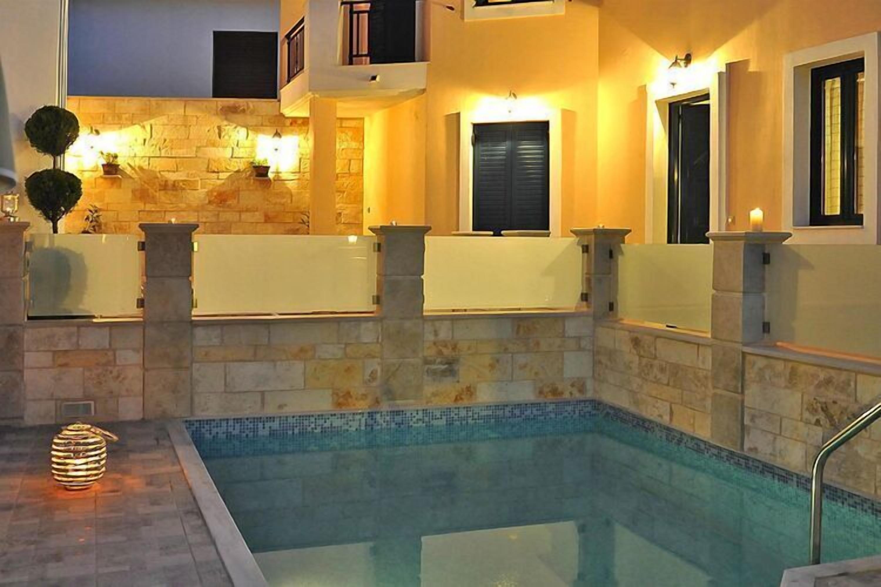 A swimming pool with stone walls and a tiled deck.