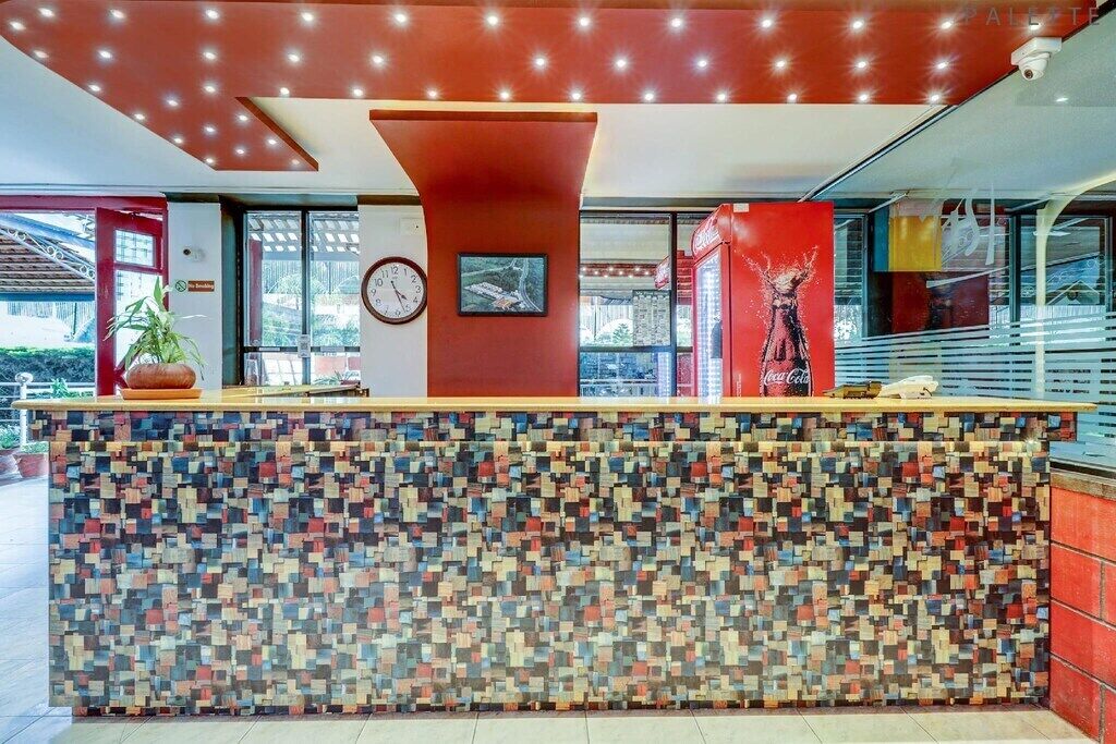 A reception area with a colorful mosaic wall, a clock, and a Coca-Cola refrigerator.