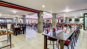 A spacious restaurant with high ceilings, stone pillars, and multiple dining areas.