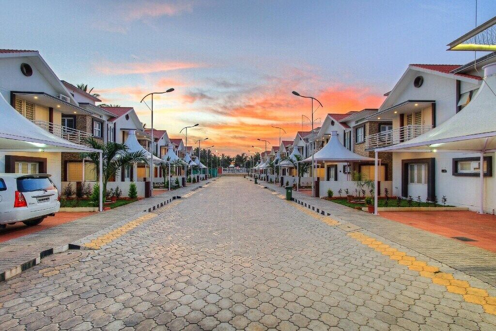 Une rangée de maisons modernes, blanches, avec des toits rouges, alignées le long d’une rue pavée dotée de revêtements de sol tactiles jaunes.