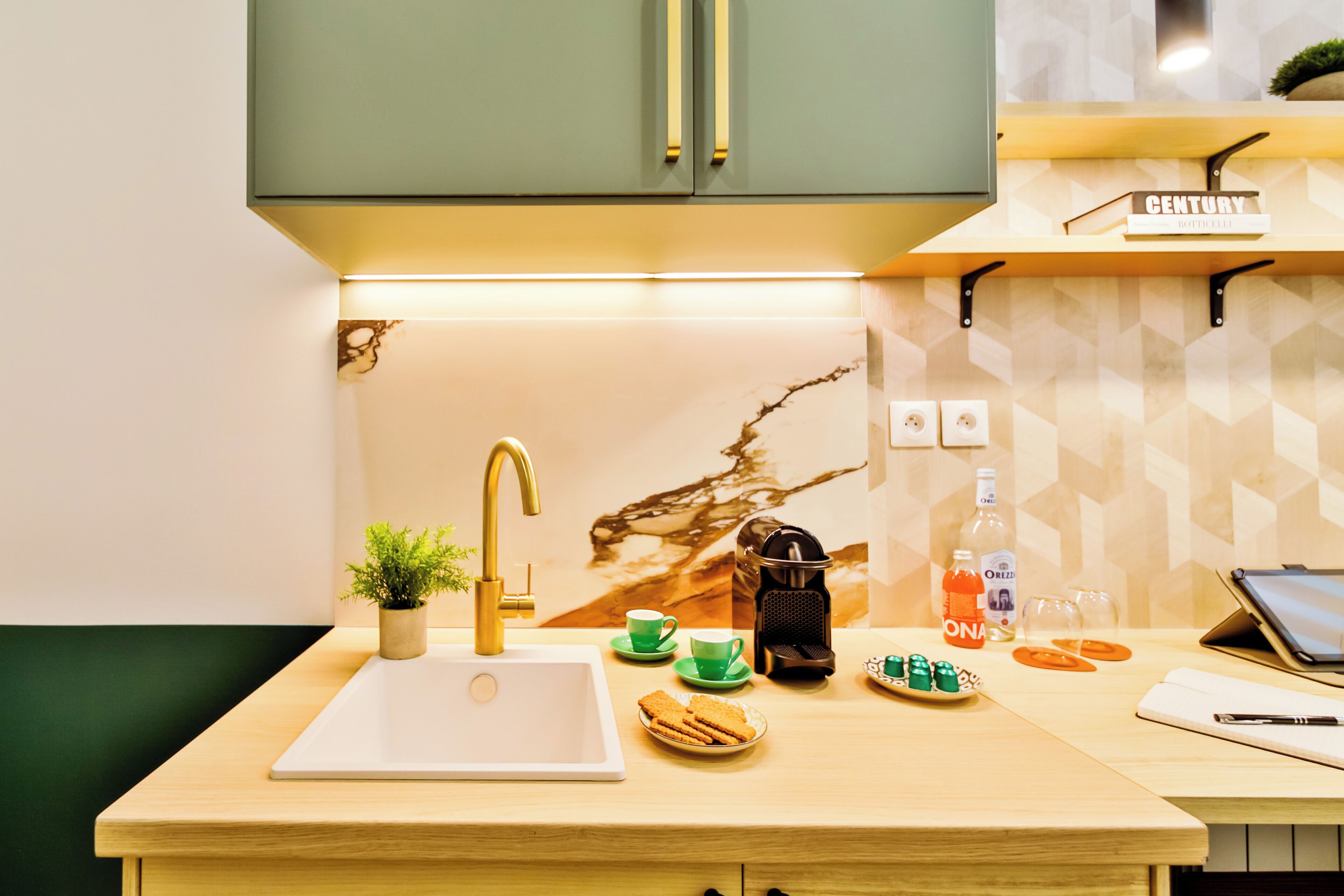 A modern kitchen with a sink, countertop, and a coffee machine.