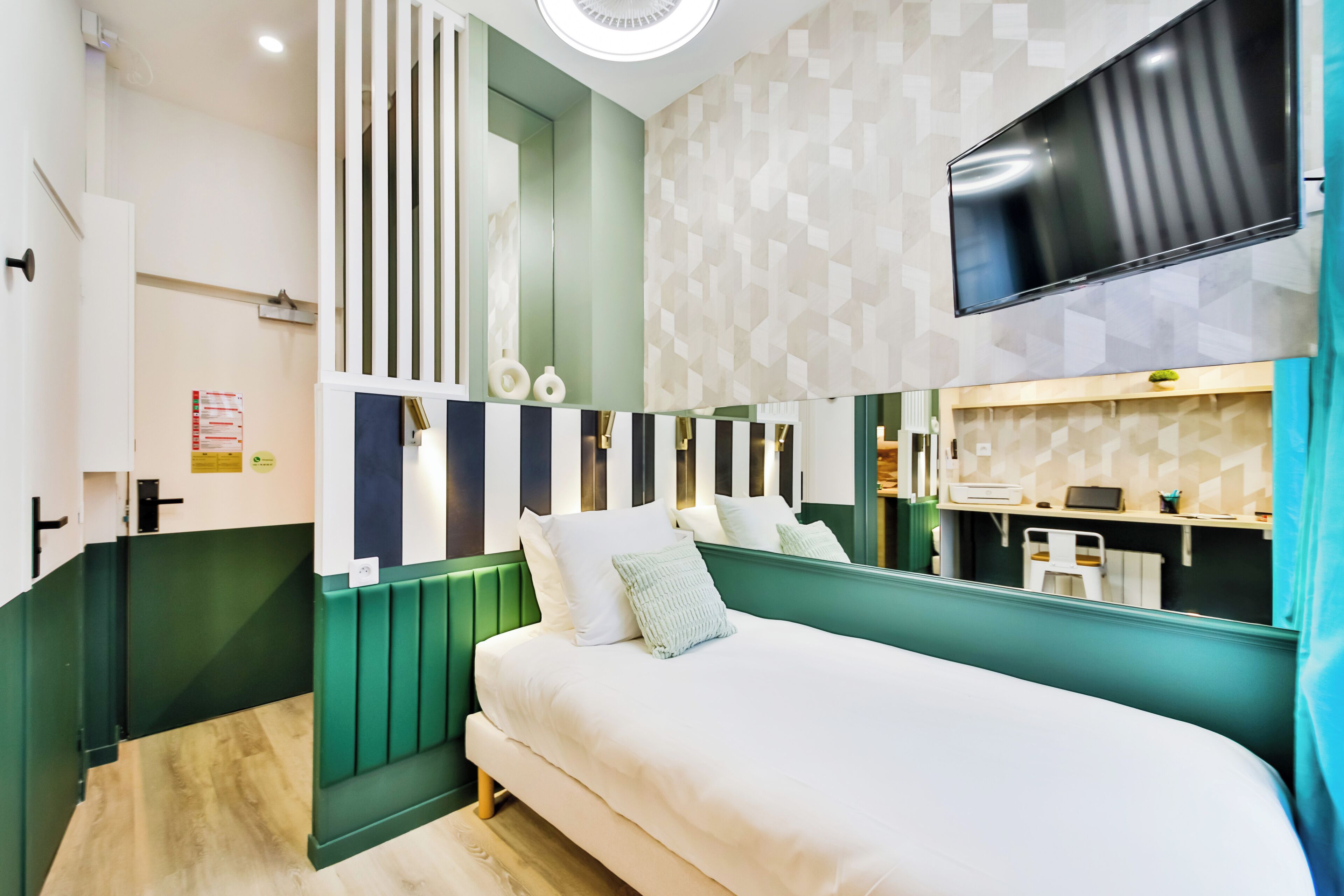 Quarto de hotel moderno com cama, televisão, escrivaninha e banheiro.
