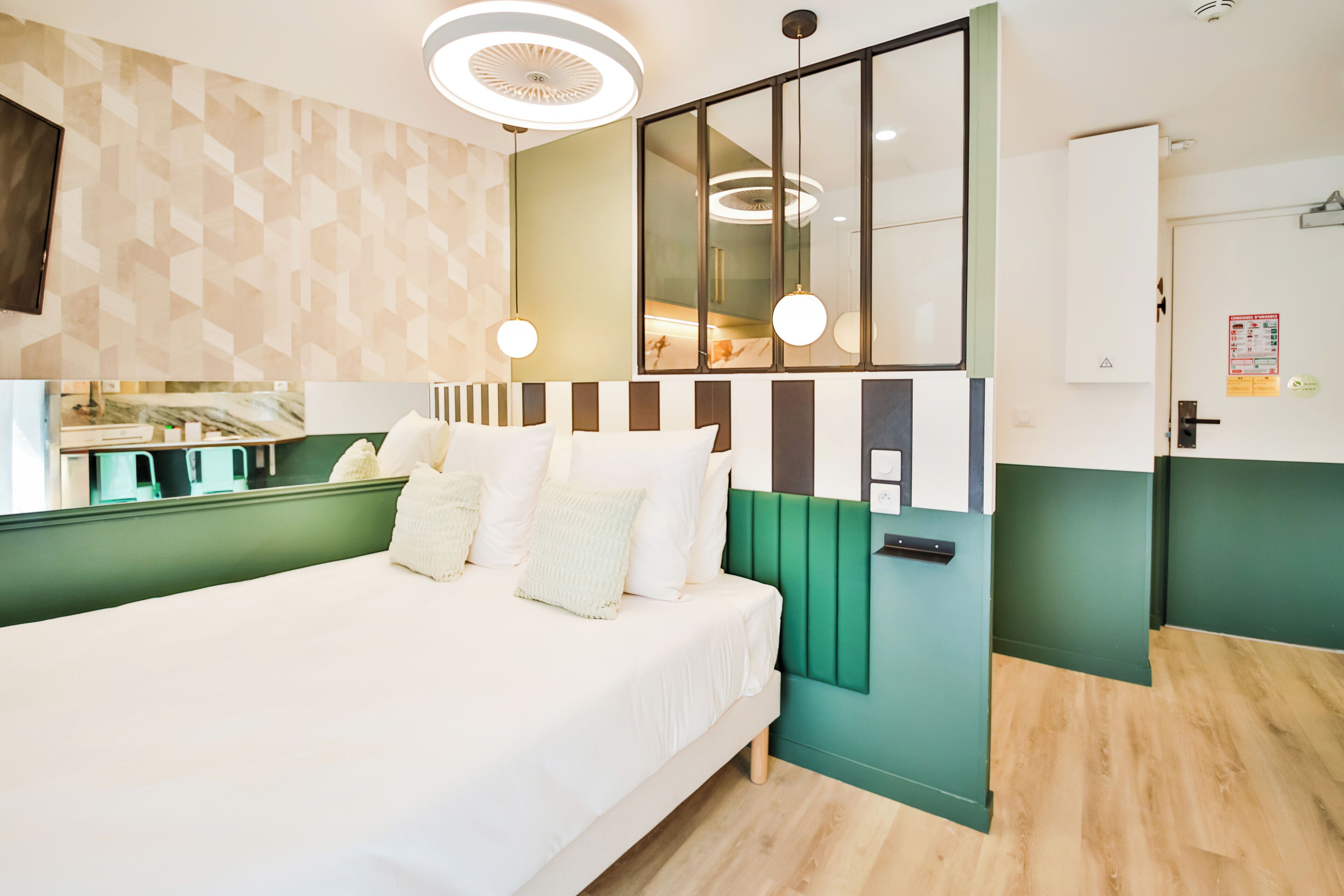 Et moderne hotelværelse med en stor seng, en grøn accentvæg og et spejlskab.