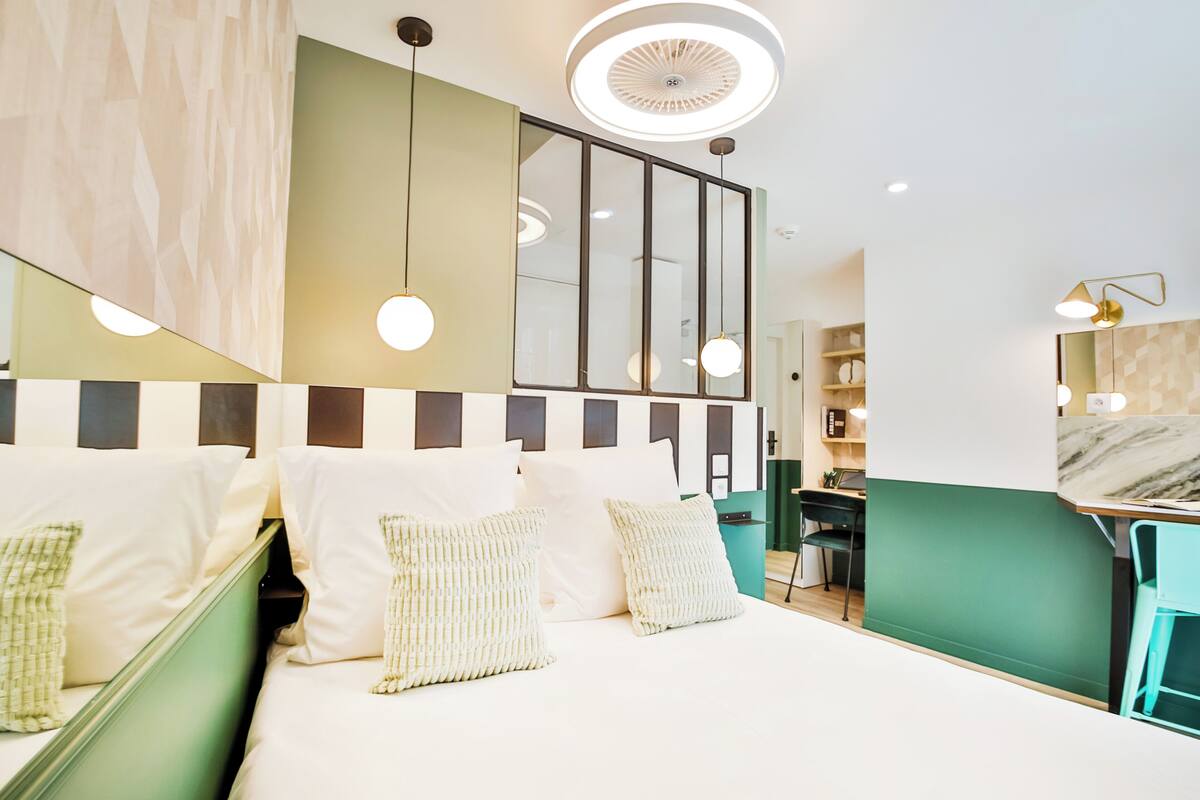 A modern hotel room with a bed, bedside tables, a desk, and a chair.