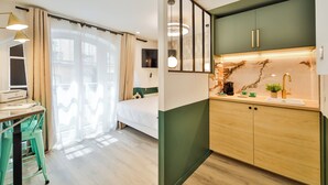 A modern hotel room with a bed, a desk, and a kitchenette. - WS Louvre - Casanova (Paris)