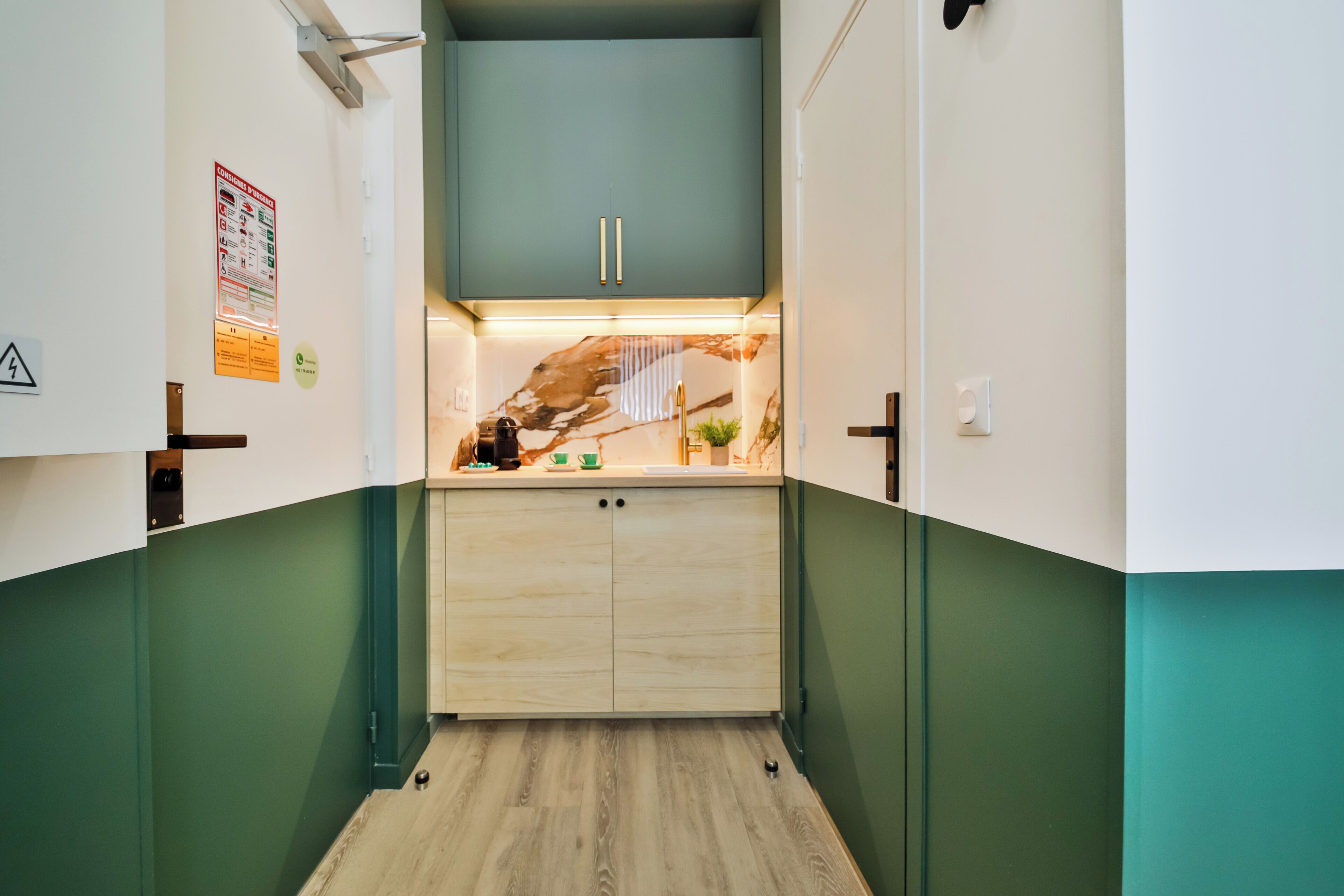 Un pasillo estrecho con un armario de madera y una pequeña zona de cocina.
