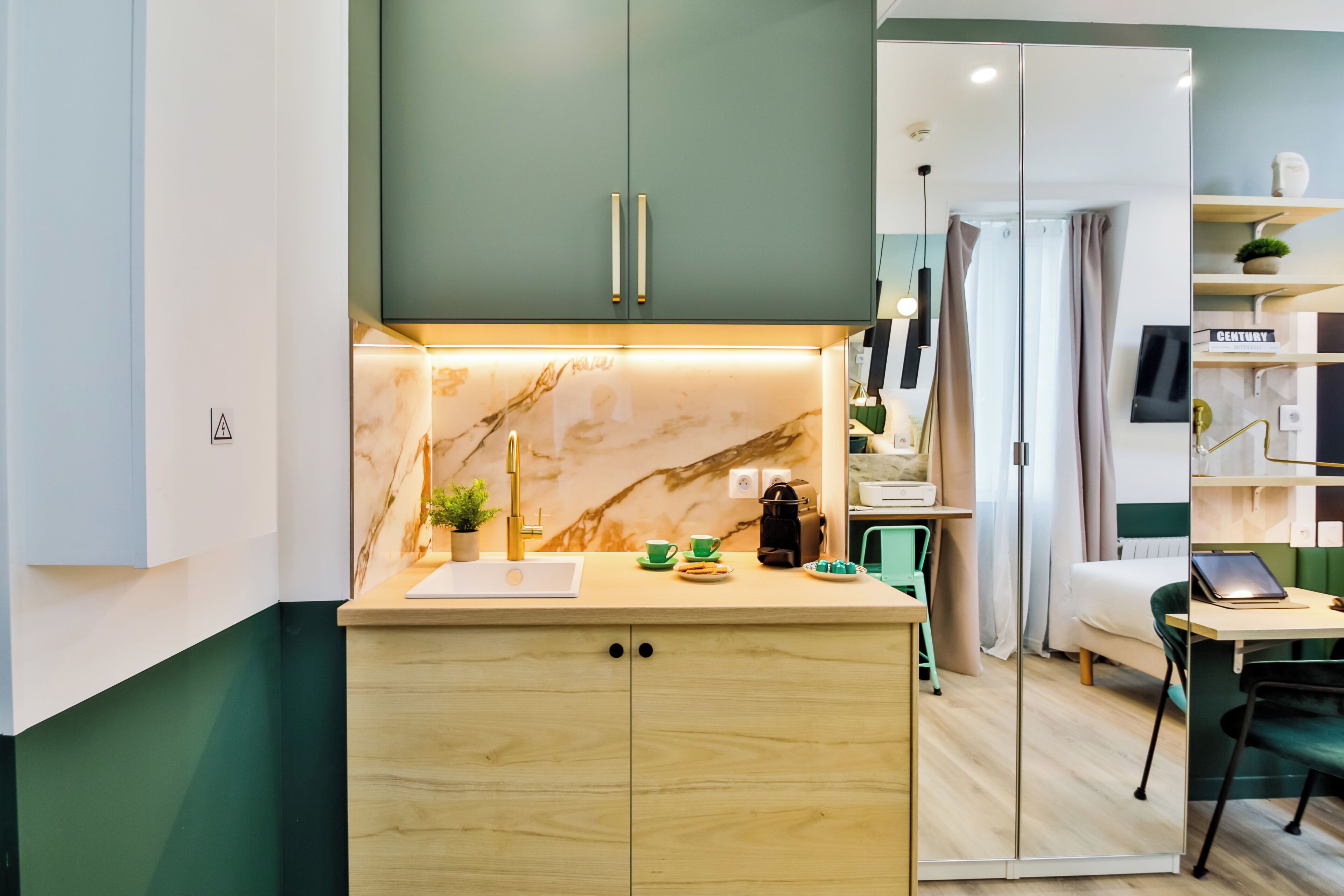 A compact kitchen with a marble countertop, a coffee machine, and a small plant.