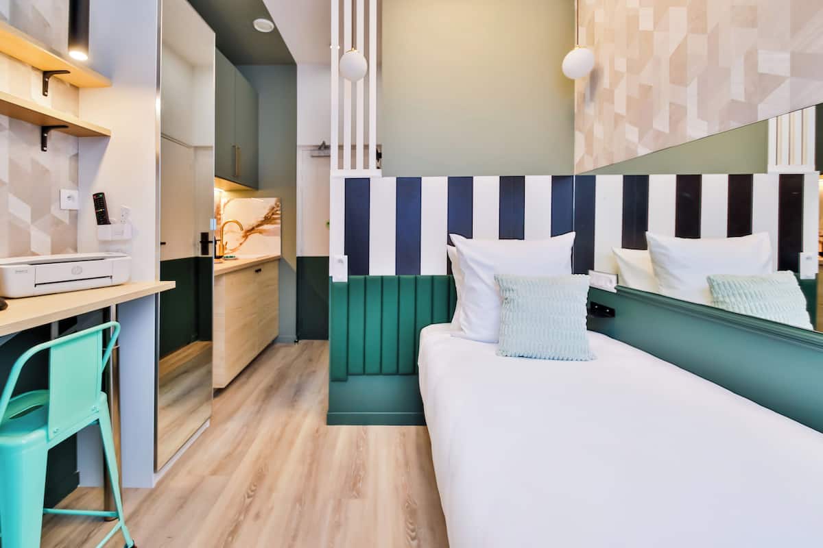 A modern hotel room with a bed, a desk, and a chair.