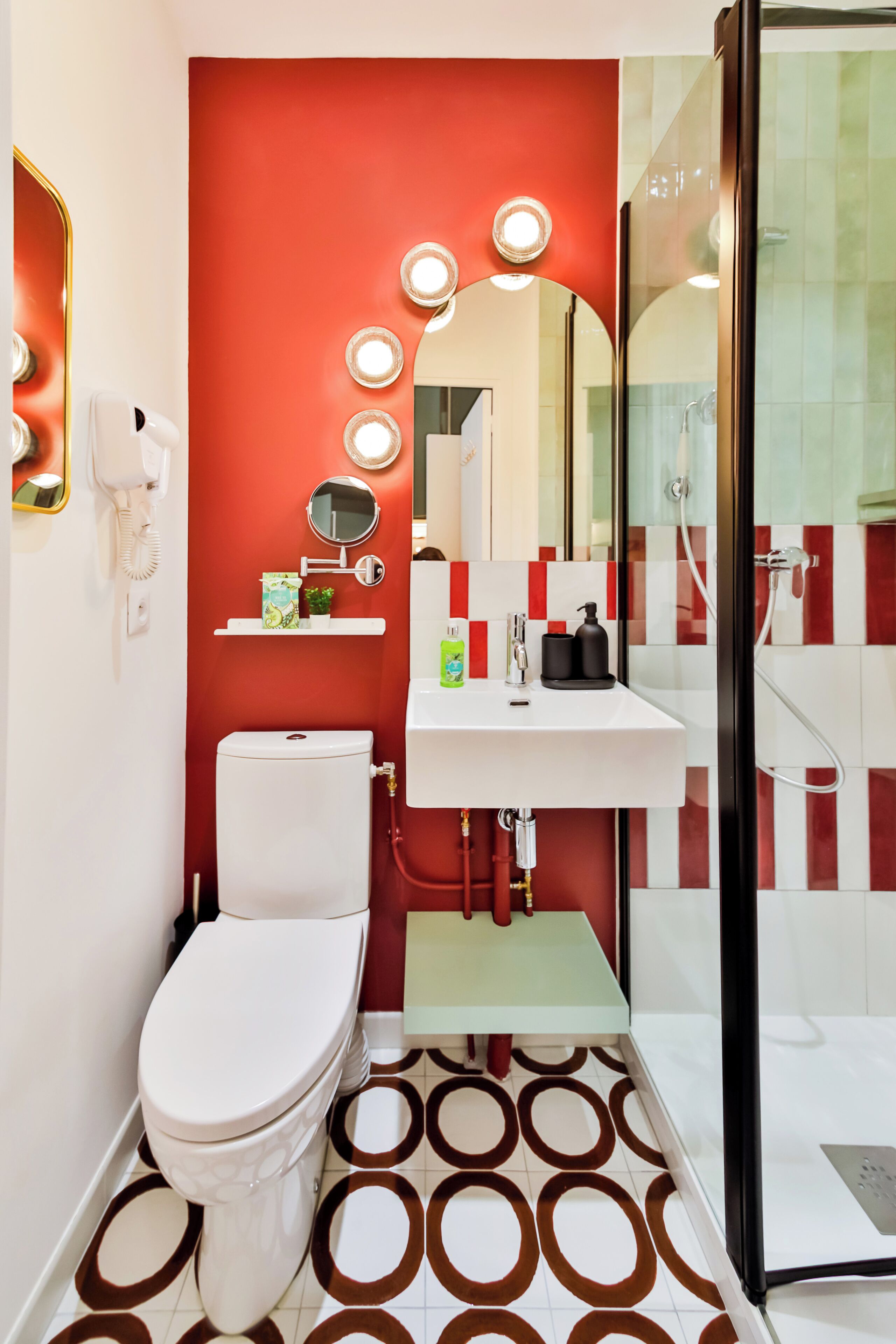 A bathroom with a white toilet, a sink with a mirror above it, and a shower area with glass doors.