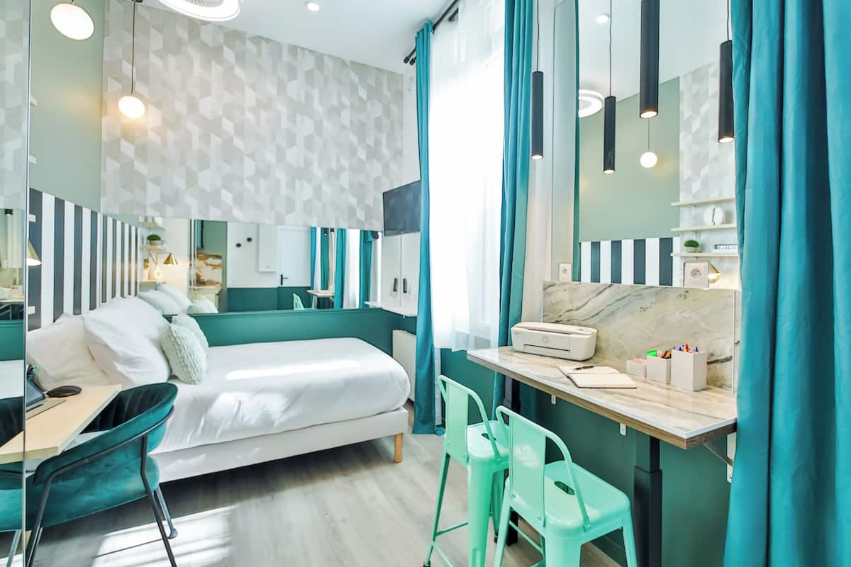 A modern hotel room with a bed, desk, chairs, and a bathroom.