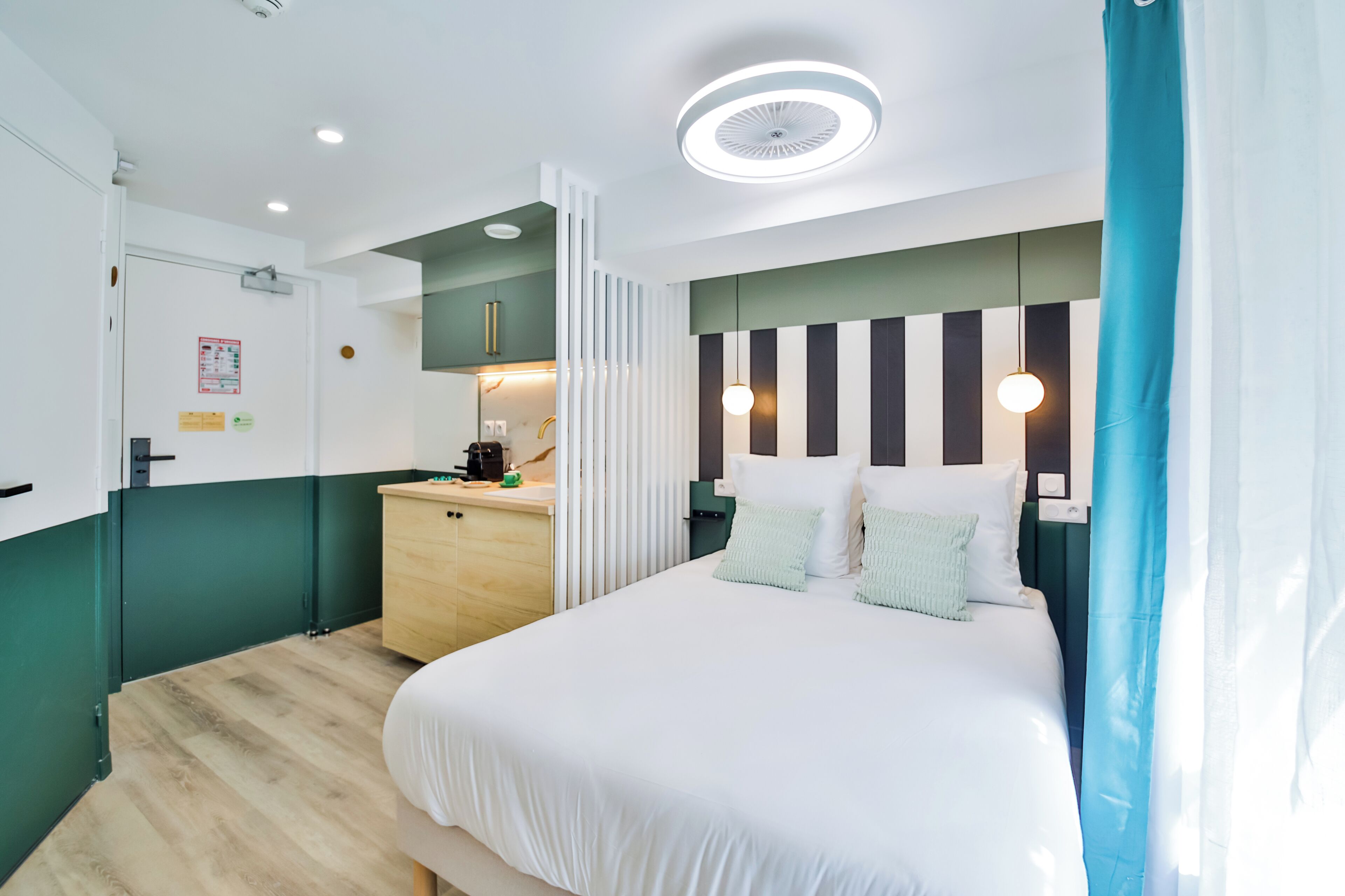 Une chambre d’hôtel moderne dotée d’un grand lit, d’une petite kitchenette et d’une salle de bain.